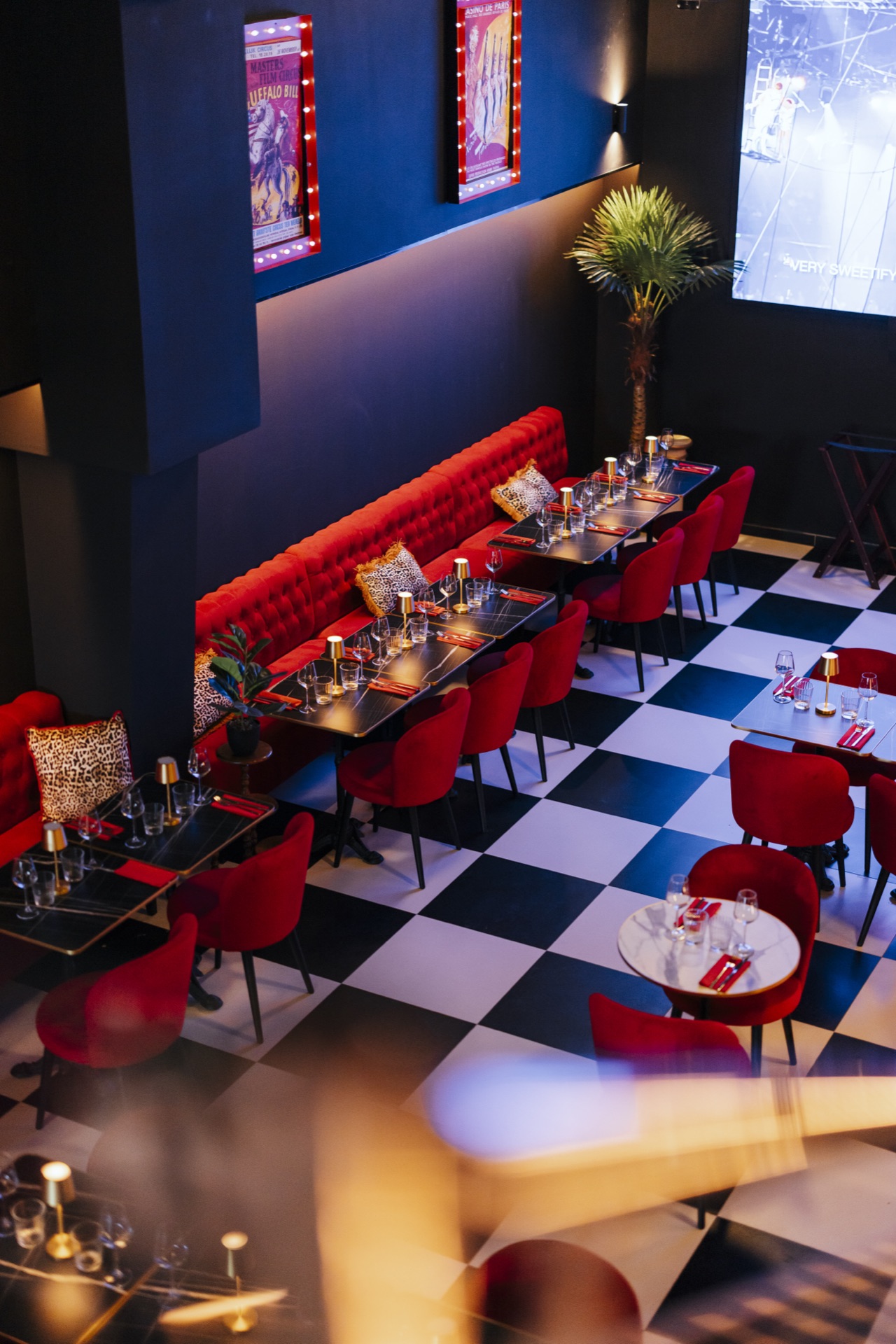 Vue plongeante de la salle bar avec banquettes rouges et écran